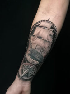 Tatuaje en colores grises de barco en brazo